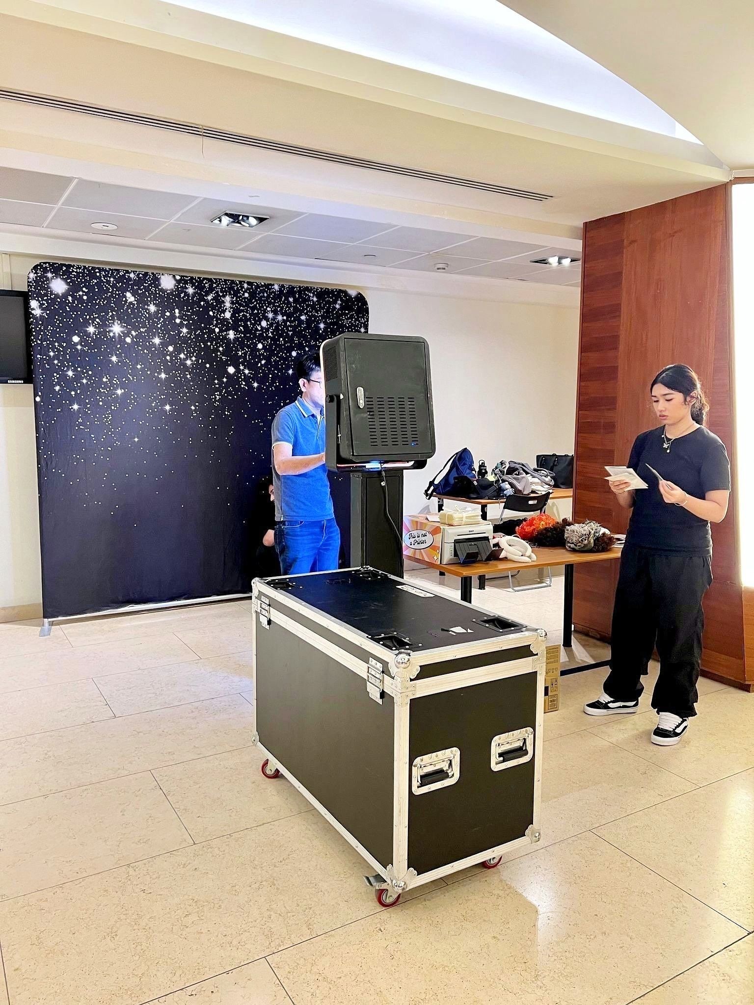 Photo booth team arranging a starry backdrop and equipment