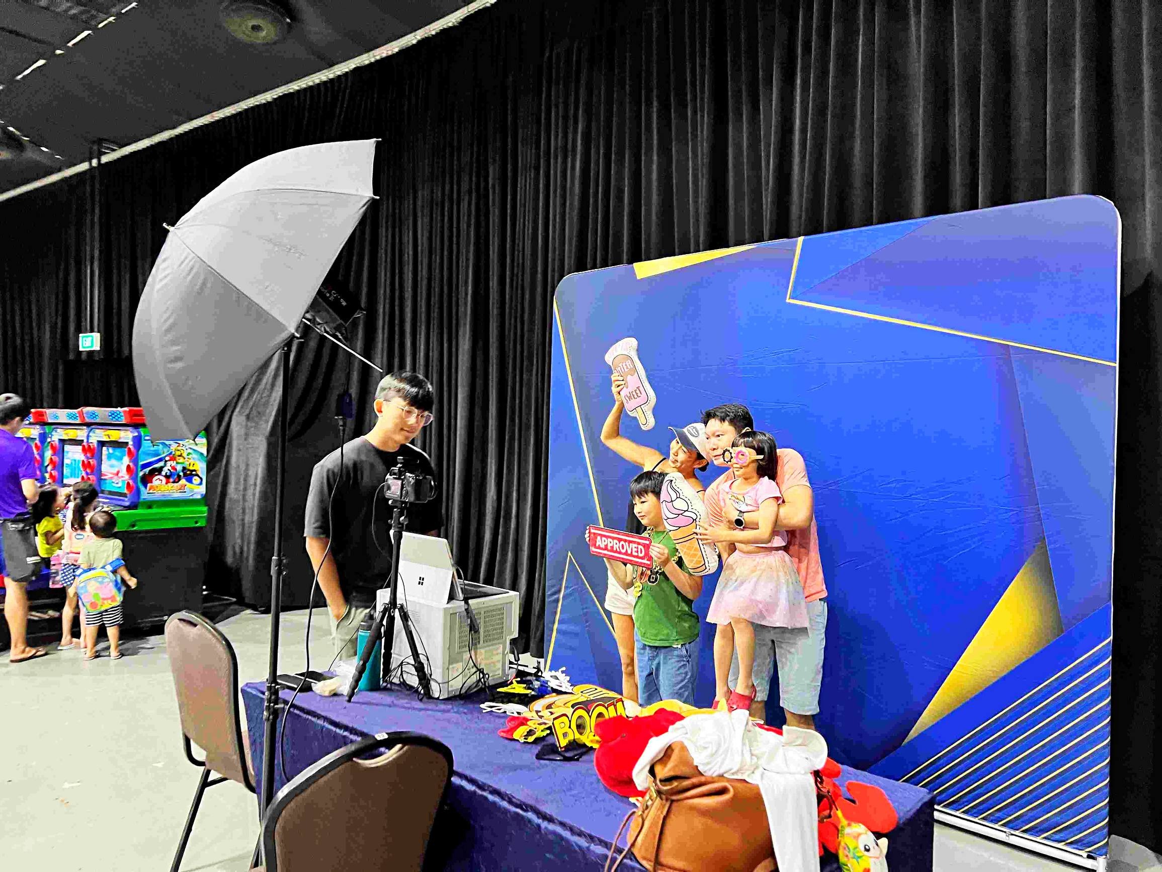 Photobooth backdrop in blue geometric colours behind a family holding props